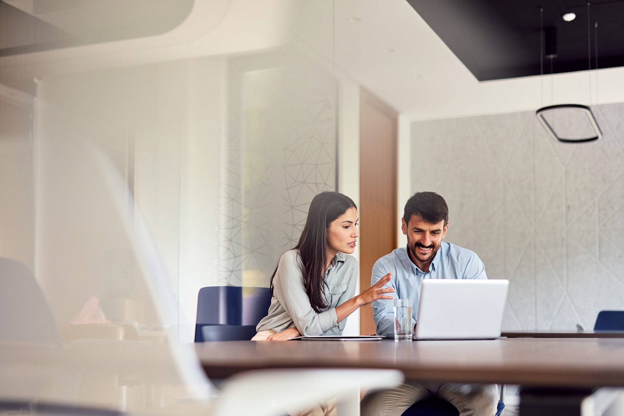 Zwei Personen arbeiten gemeinsam an einem Laptop in einem hellen Büro